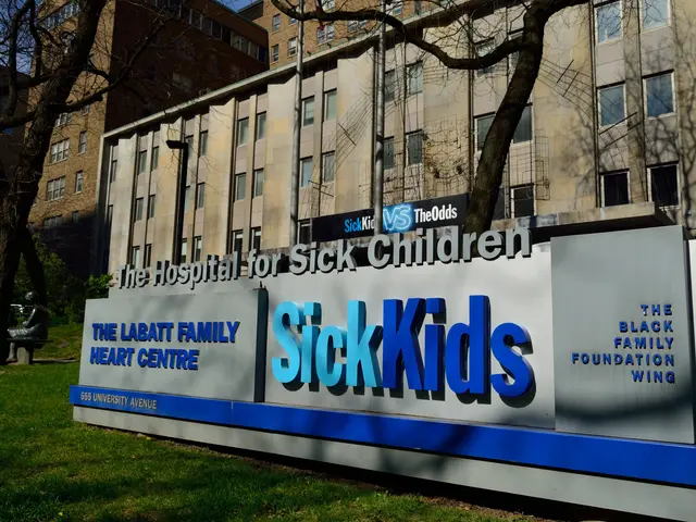 The image shows the hospital for sick children, with a name board in the foreground, grass on the...