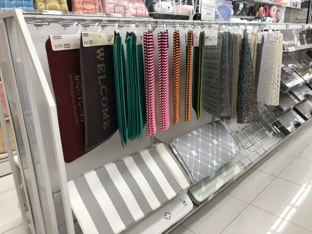 The image shows a store filled with lots of different types of carpets and rugs on display. There...