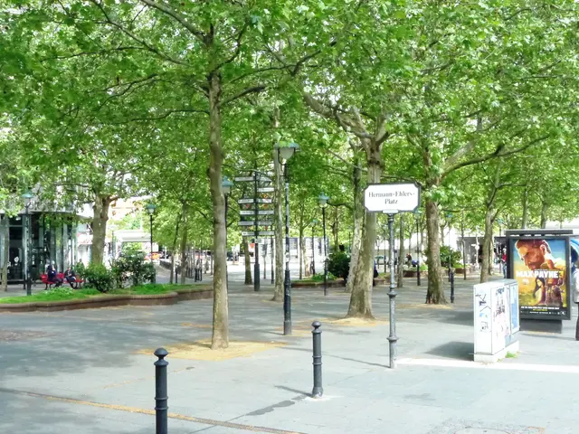 The image shows a city street filled with lots of trees and people walking down it. There are...