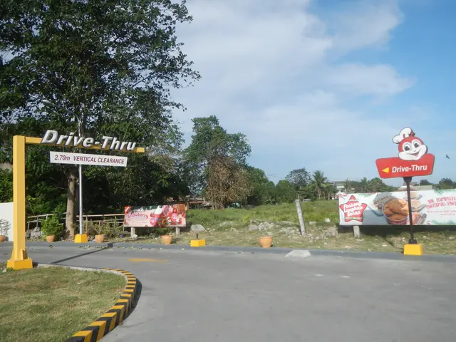 The image shows the entrance to a drive-thru restaurant in the Philippines, with a road, grass,...