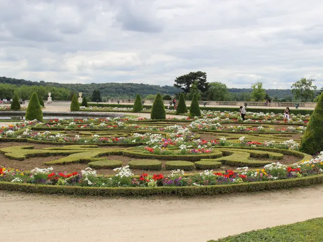 The image shows a formal garden in the middle of a park with a variety of plants, flowers, trees,...
