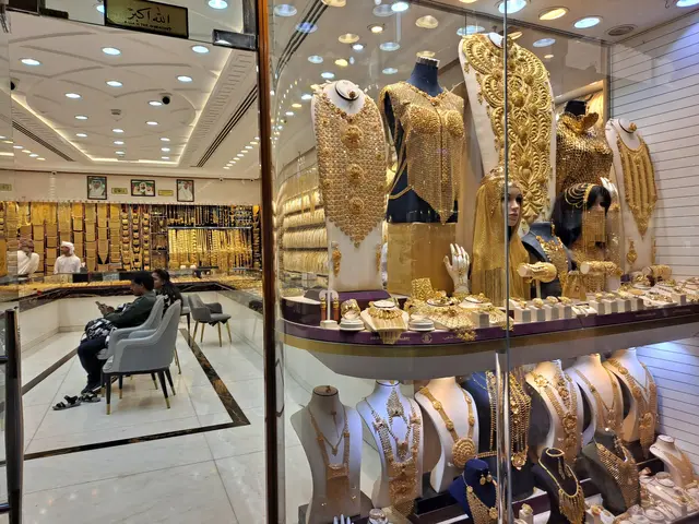 The image shows a store filled with lots of gold jewelry, including mannequins wearing ornaments,...
