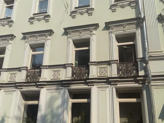 The image shows a building with many windows and balconies on the side of it, along with railings,...