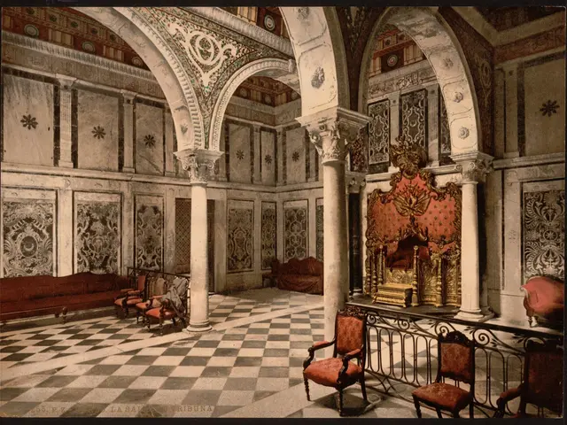 The image shows an old photo of a room with a checkered floor, chairs, sofas, pillars, a railing,...