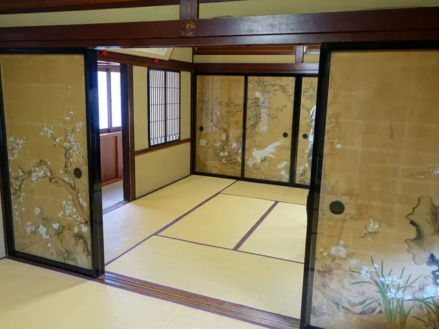 The image shows a room with tatami mats on the floor, paintings on the walls, glass doors, windows,...
