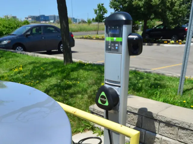 The image shows an electric car plugged into a charging station on the side of a road, surrounded...