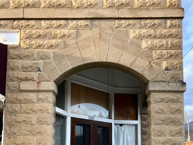 The image shows an old stone building with a wooden door and windows, a doormat on the floor, a car...