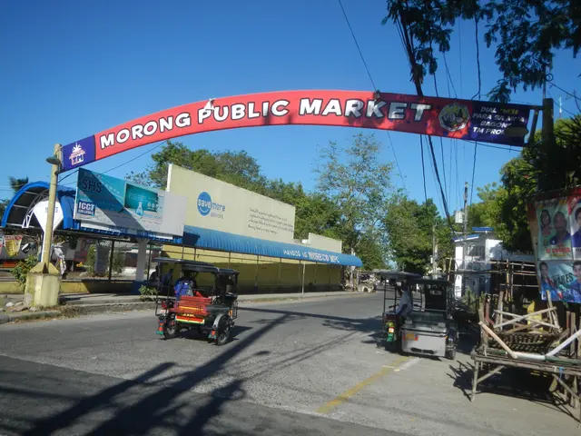The image shows the entrance to the Morong Public Market in the Philippines, with vehicles on the...