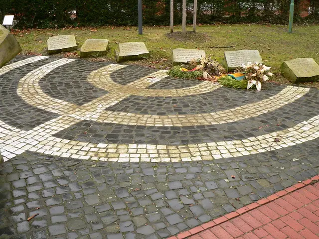 The image shows a memorial in the middle of a park with a circular design on it. On the left side...