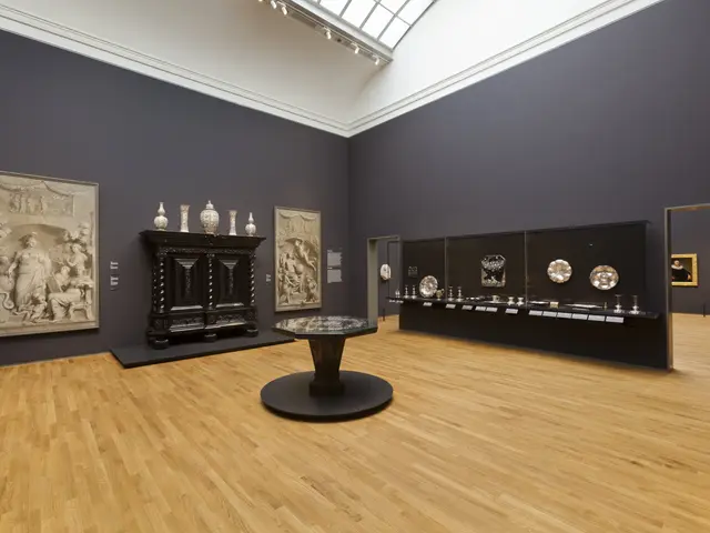 The image shows a large room filled with lots of art on display, including a table on the floor,...