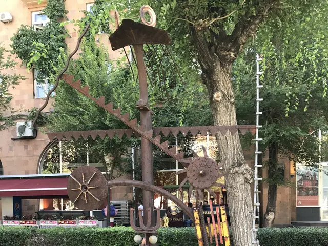 The image shows a metal sculpture in the middle of a grassy area next to a tree, surrounded by...
