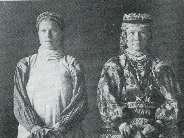The image shows two women in traditional Russian clothing standing side by side against a dark...