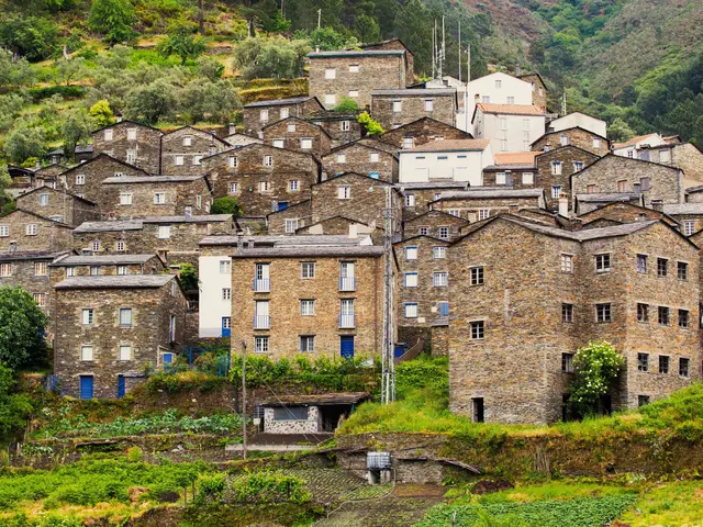 The image shows a small village nestled in the middle of a lush green hillside, with a number of...