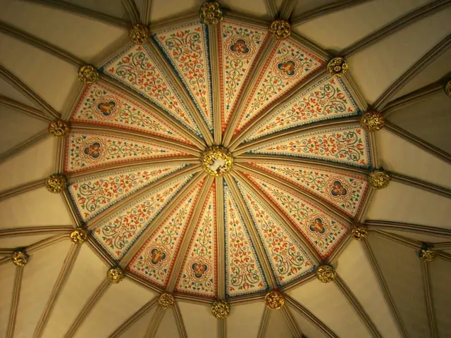 The image shows the interior of a cathedral with a rose vaulted ceiling and stained glass windows....
