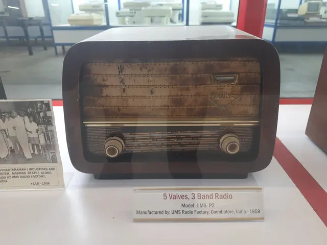 The image shows an old radio sitting on top of a white table, with a name board and a photo frame...