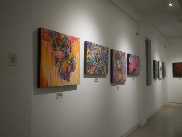 The image shows a room with paintings on the wall, illuminated by lights from the ceiling. The...