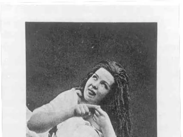 The image shows a black and white photo of a woman laying in bed, with a bed sheet draped over her....