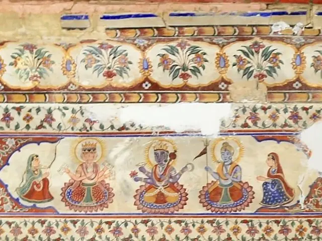 The image shows a painting on the wall of a building in Rajasthan, India, depicting a scene from a...